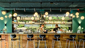 A bar area with wooden bar counters, black bar stools, and hanging spherical lights. - Conscious Hotel Westerpark (Amsterdam)