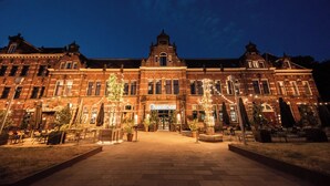 A historic building with a central entrance, multiple windows, and outdoor seating areas with umbrellas. - Conscious Hotel Westerpark (Amsterdam)