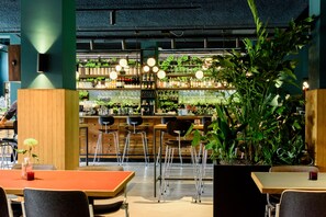 L’intérieur d’un restaurant avec des sièges au bar, un comptoir et des plantes en pot.