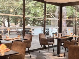 Un comedor interior con mesas y sillas, ventanas amplias y vistas al exterior.
