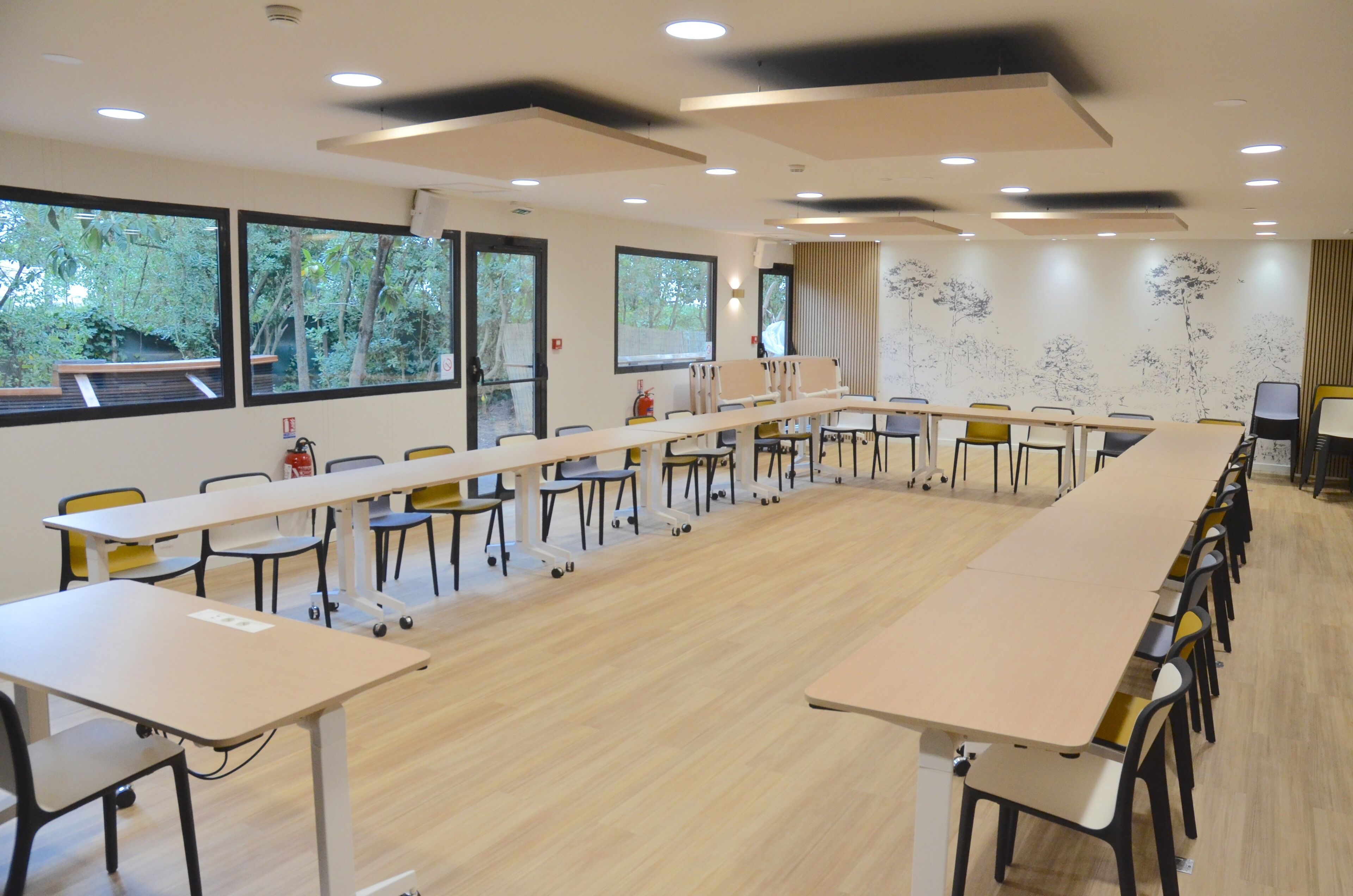 Une salle de conférence avec une longue table, des chaises et de grandes fenêtres.