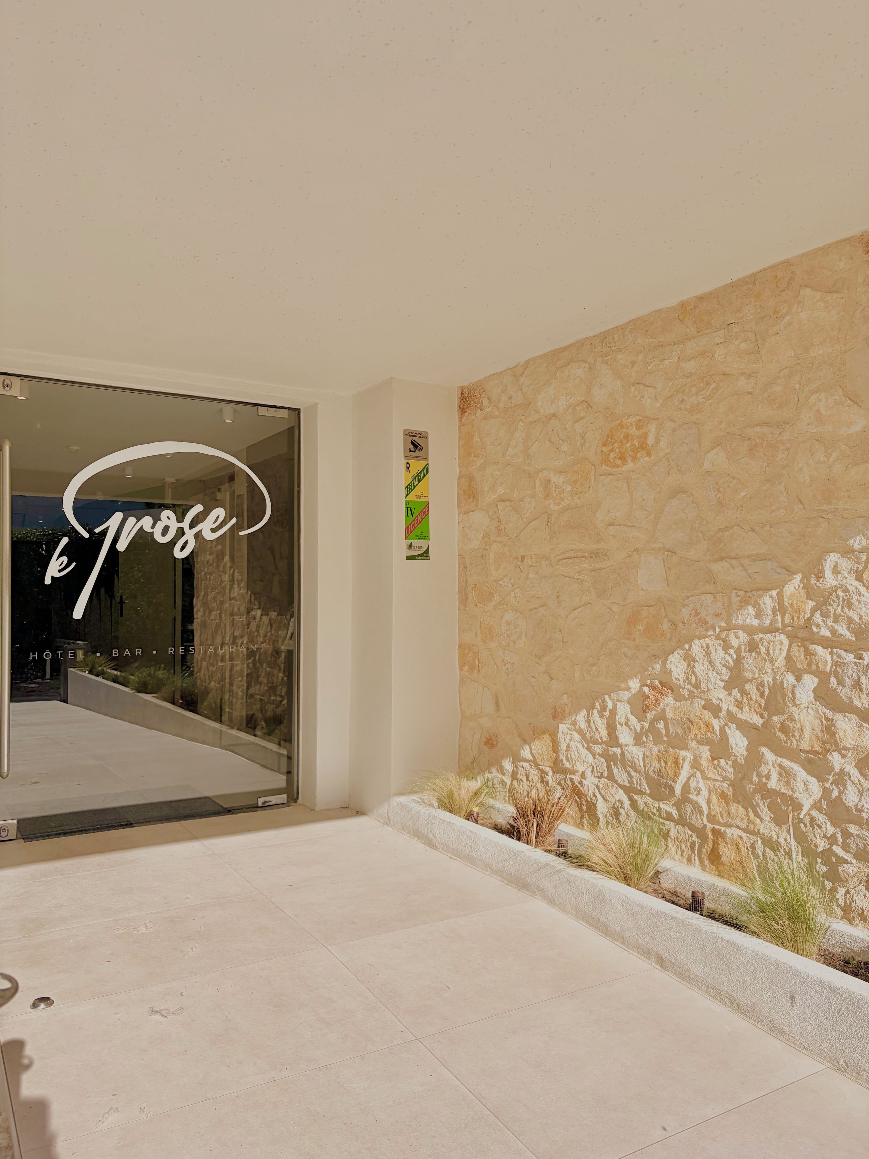A hotel entrance with a stone wall and a glass door.