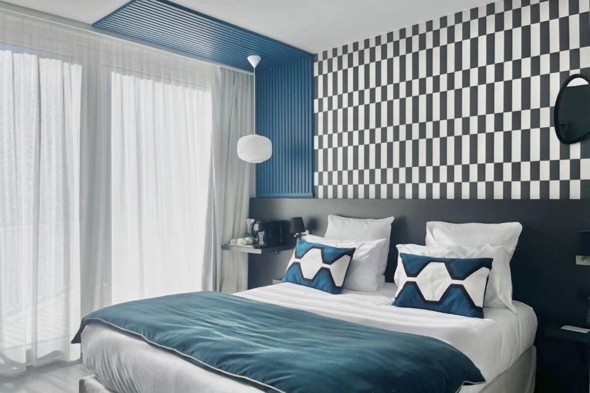 Habitación de hotel moderna con una cama grande, un diseño de pared a cuadros y vistas al exterior.