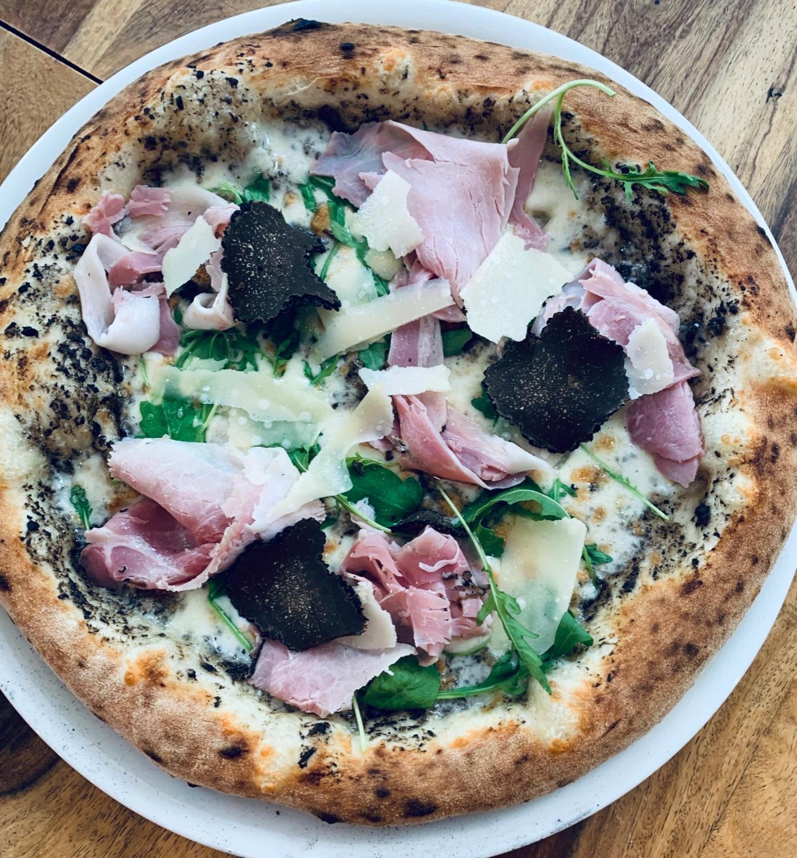 Una pizza amb diferents ingredients sobre un plat blanc.