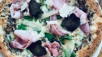 Una pizza amb diferents ingredients sobre un plat blanc.