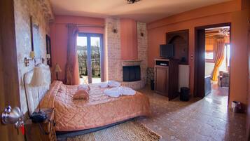 A bedroom with a bed, a fireplace, a television, and a view of the outdoors.
