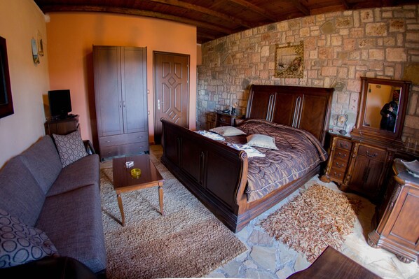 Un dormitorio con cama, armario de madera y pared de piedra.