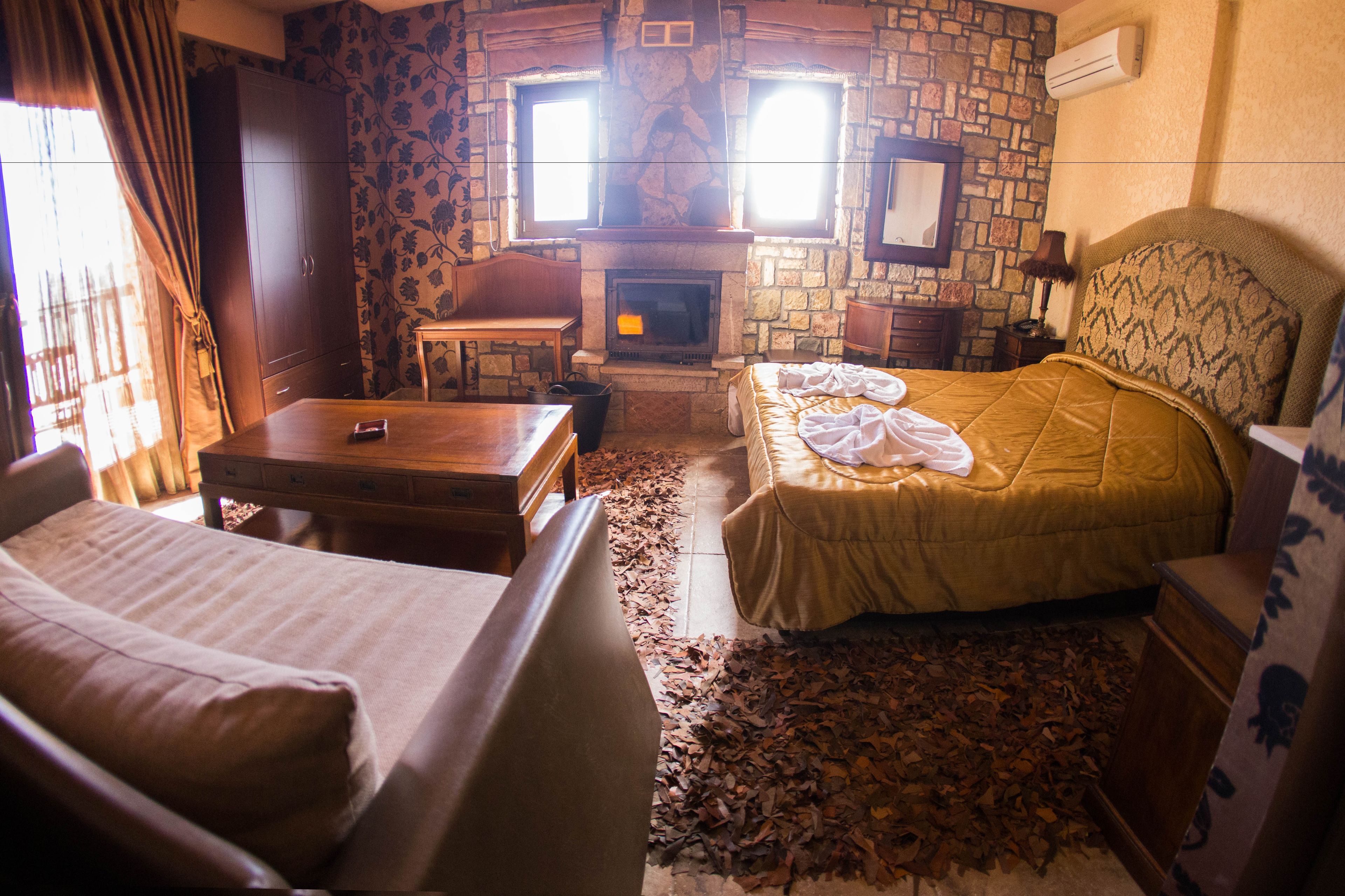 A cozy room with a stone fireplace, a bed, a table, and a wardrobe.