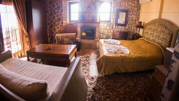 A cozy room with a stone fireplace, a bed, a table, and a wardrobe.