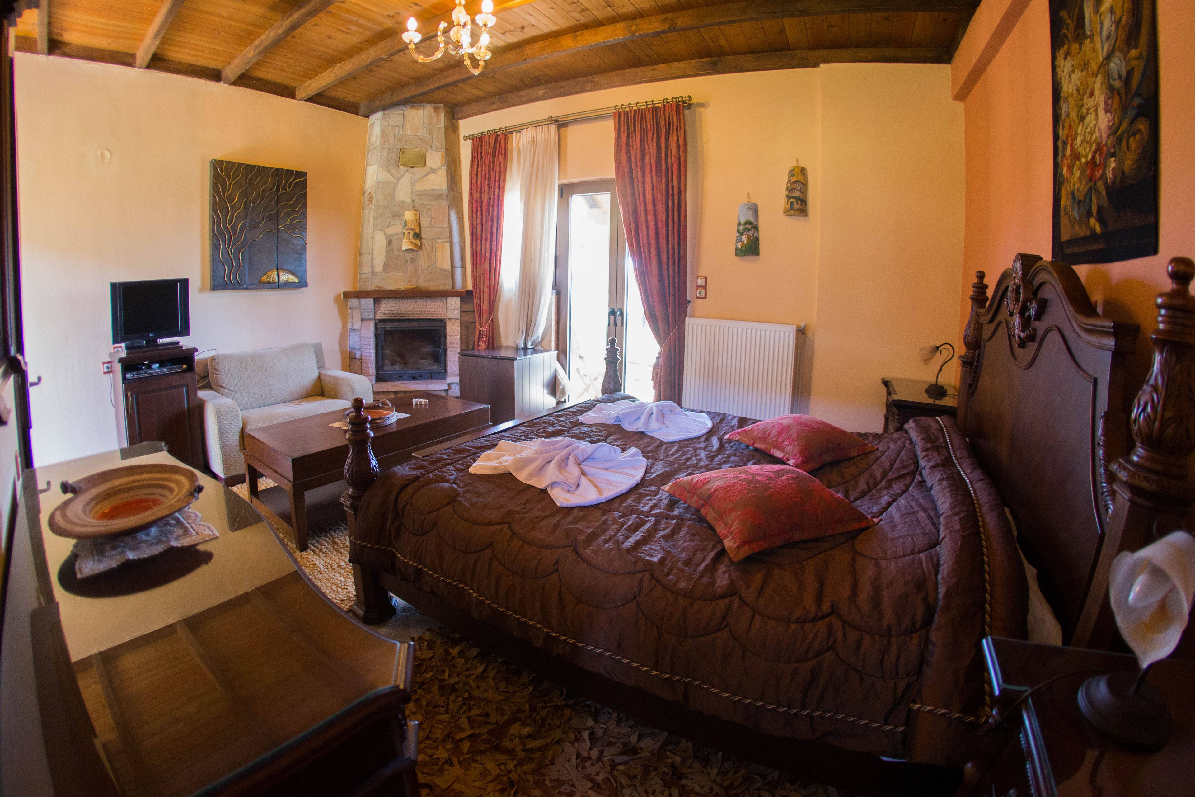 A cozy bedroom with a large bed, a fireplace, a television, and a dining area.