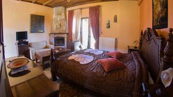 A cozy bedroom with a large bed, a fireplace, a television, and a dining area.
