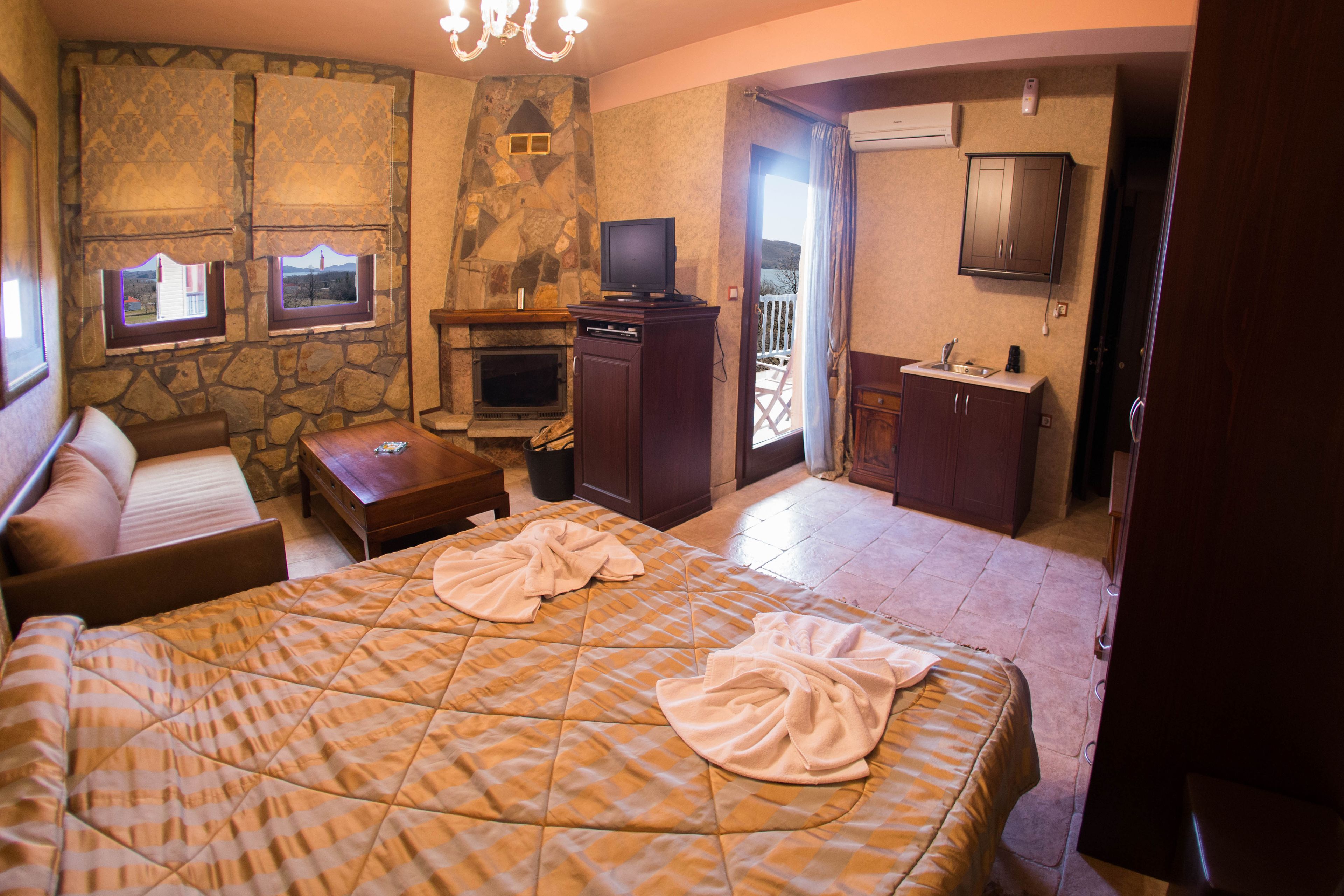 A hotel room with a bed, a television, a fireplace, and a balcony.