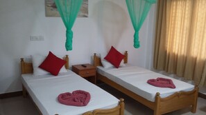 Two single beds with wooden frames, white linens, red pillows, and a small bedside table with a remote control. - Oasis Beach Resort (Negombo)