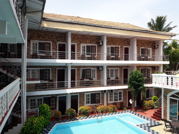 A multi-story building with a pool area, balconies, and a staircase leading to the upper floors. - Oasis Beach Resort (Negombo)