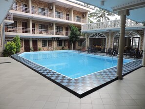 An indoor swimming pool with a checkered border, surrounded by a building with multiple balconies and a covered seating area. - Oasis Beach Resort (Negombo)