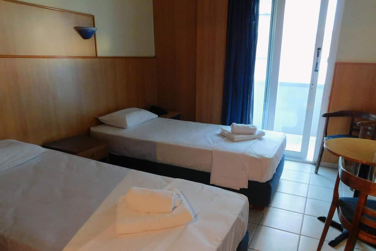 Una habitación de hotel con dos camas, un cabecero de madera, una mesita y una silla.