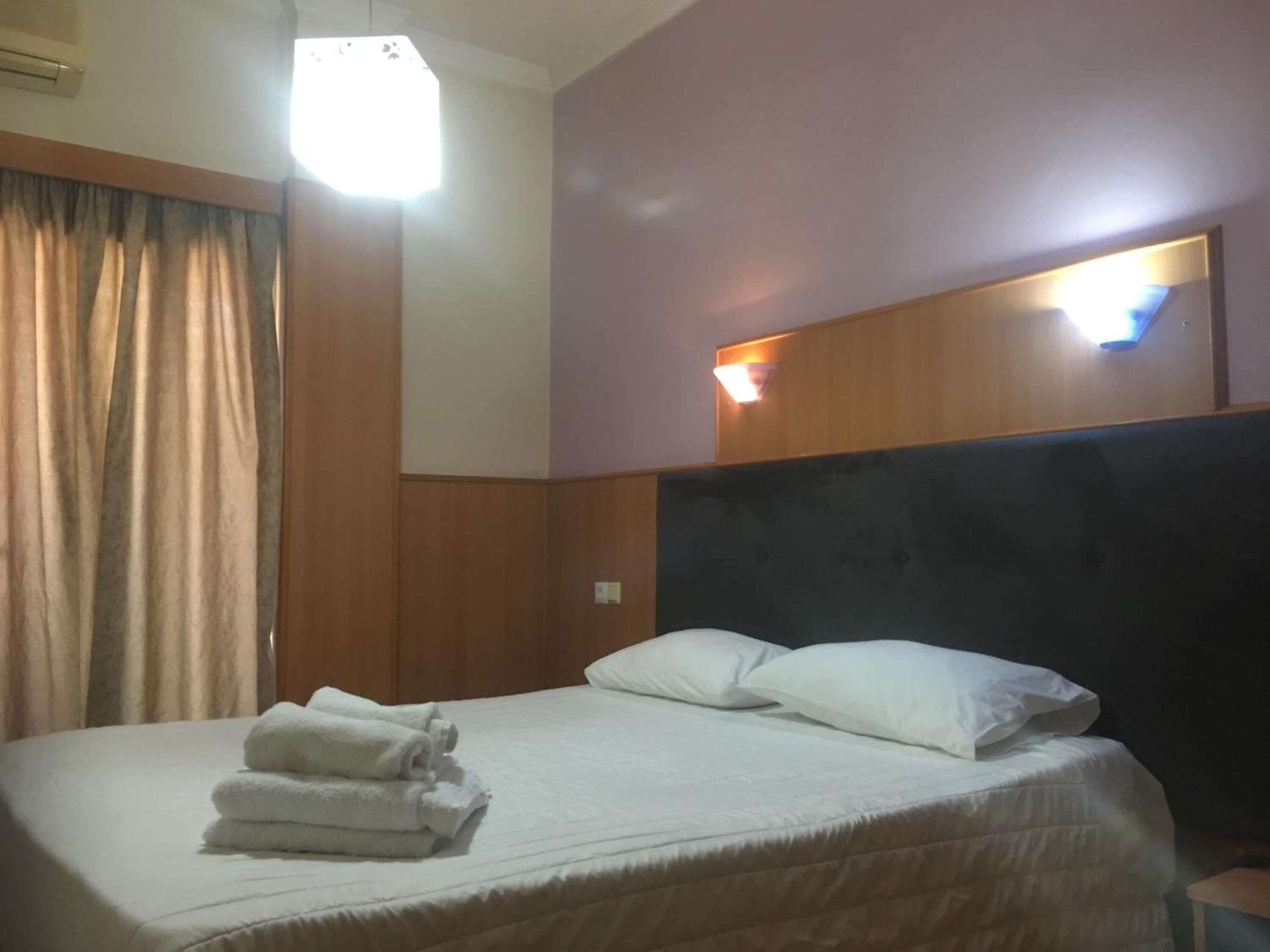 A hotel room with a bed, a headboard, and a nightstand.