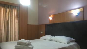 A hotel room with a bed, a headboard, and a nightstand.
