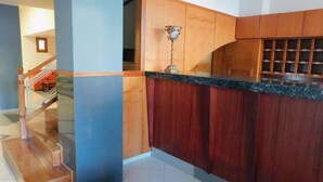 A modern kitchen with wooden cabinets, a marble countertop, and a staircase leading to an upper level.