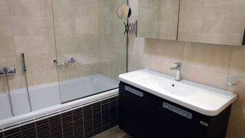 A modern bathroom with a glass-enclosed shower, a white sink, and a black cabinet.
