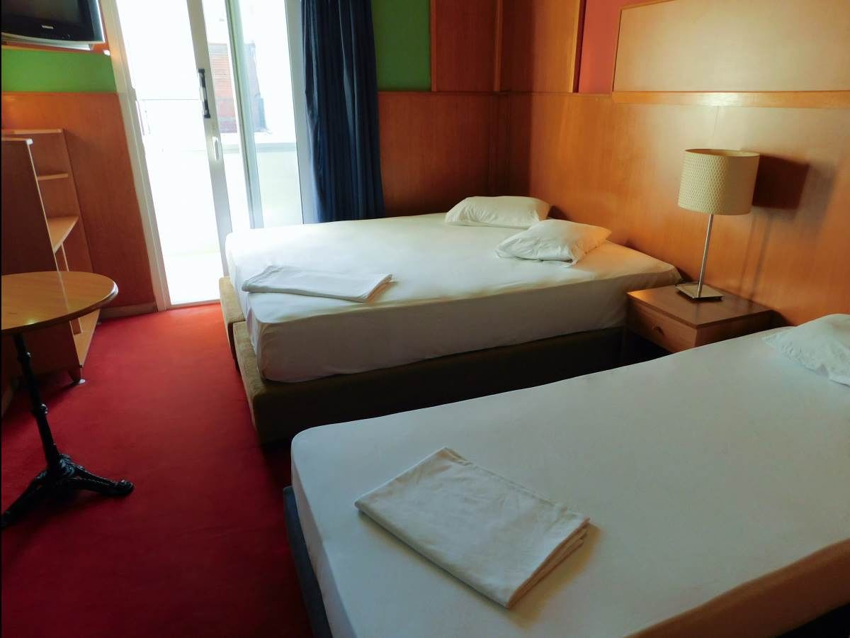 A hotel room with two beds, a small table, and a TV.