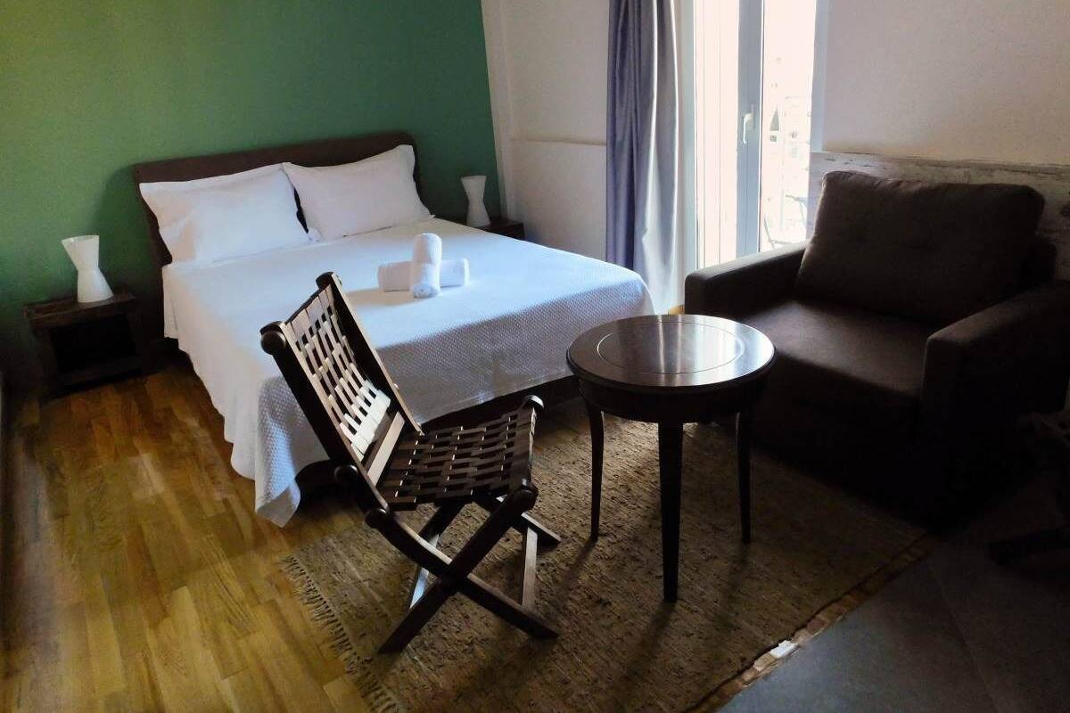 Una habitación de hotel con una cama, una silla, una mesita y un sofá.