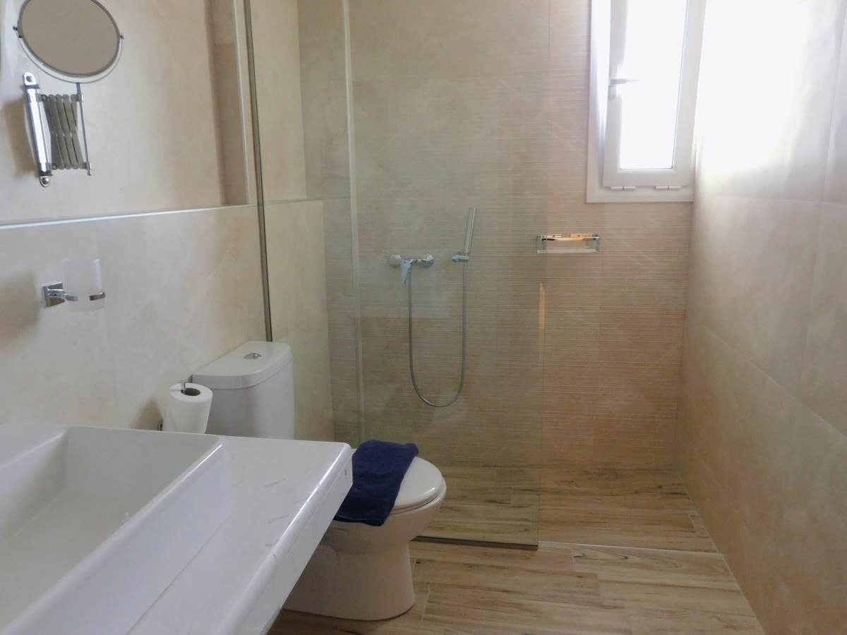 A bathroom with a bathtub, toilet, and glass-enclosed shower.