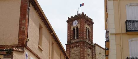 Una calle con un edificio histórico que presenta una torre de reloj, un letrero que dice 'Edifice', y una barricada con un cartel de 'Policía Municipal'.