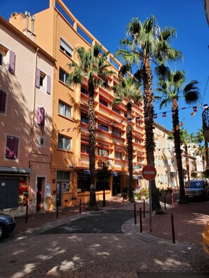 A multi-story hotel with balconies, palm trees, and a clear blue sky. - Hôtel le Richelieu (Le Boulou)