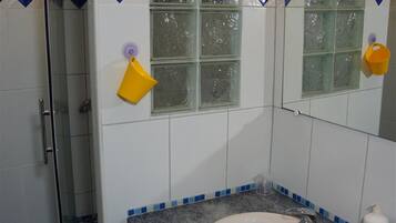 A bathroom with a sink, mirror, and a shower area.