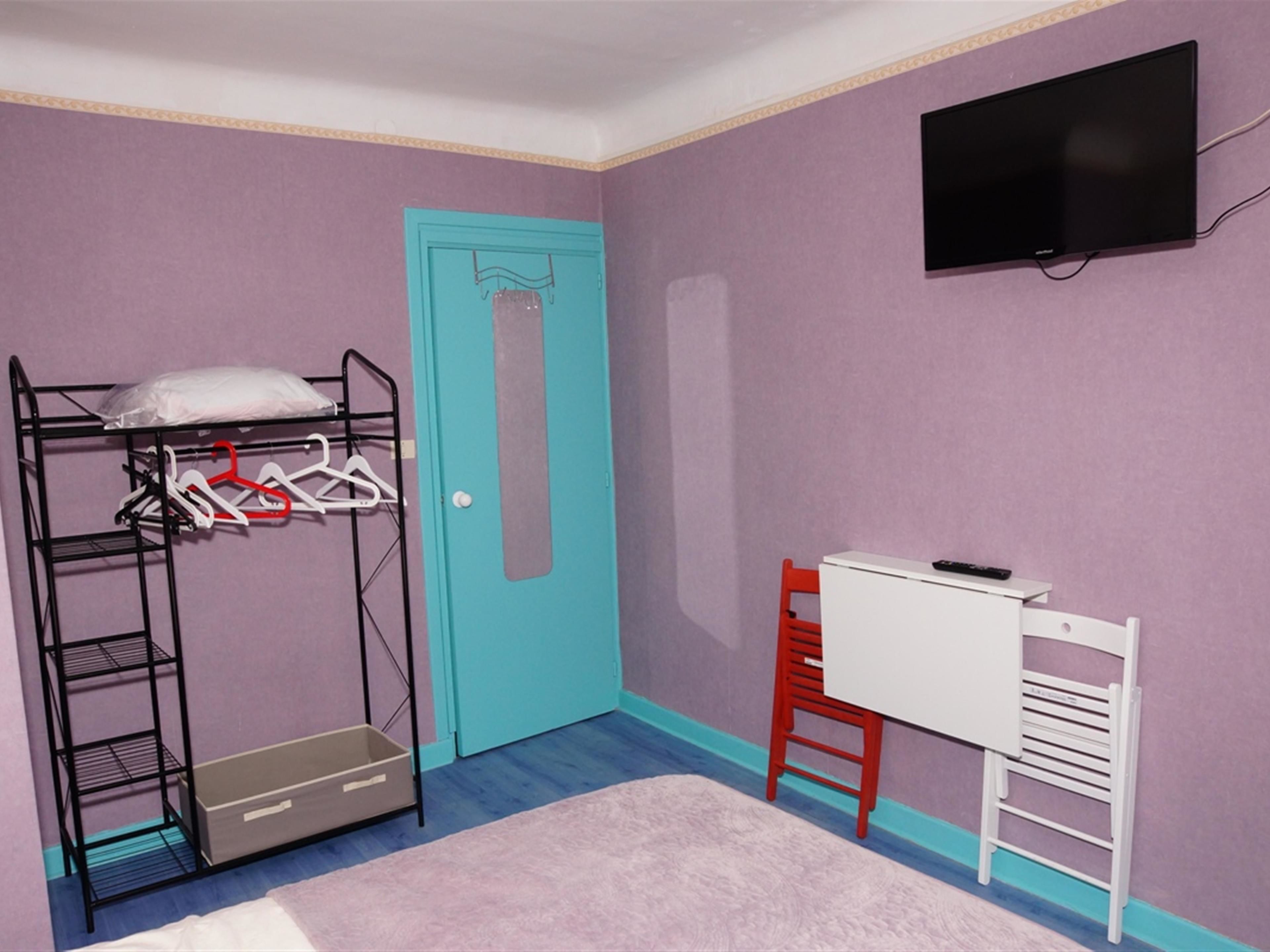 A room with a bunk bed, a desk, a chair, and a television.