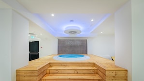 A modern spa area with a wooden hot tub and steps leading up to it.