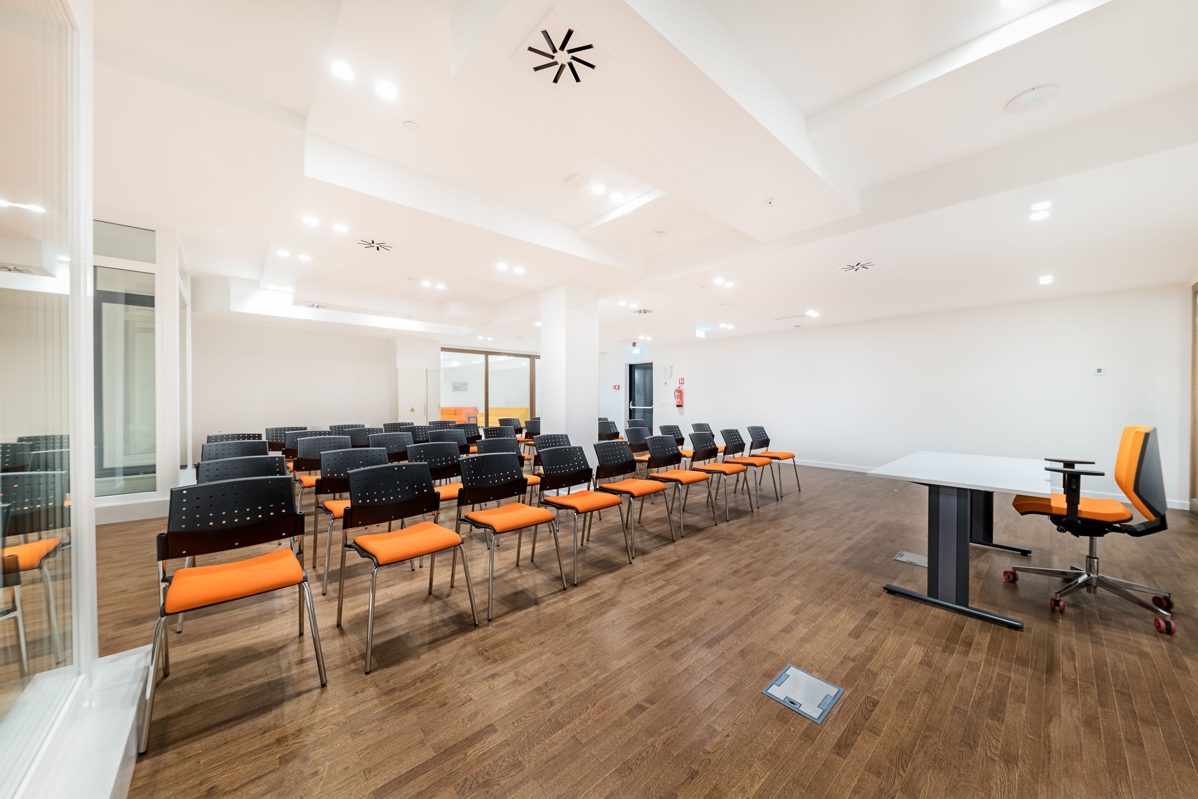 A conference room with rows of chairs, a table, and a modern ceiling design.