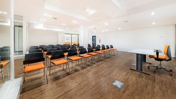 A conference room with rows of chairs, a table, and a modern ceiling design.