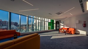 A modern interior with large windows, a sofa, a coffee table, and a green accent wall.