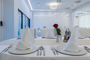 Comedor con vajilla blanca, que incluye platos, cubiertos y servilletas.