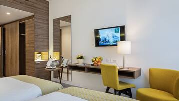 Habitación de hotel con dos camas, un escritorio con silla, televisor y lámpara.