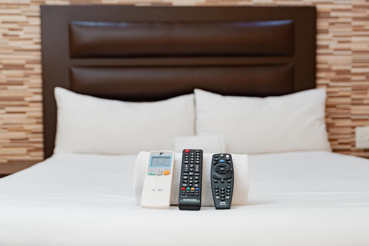 A bed with three remote controls placed on it.