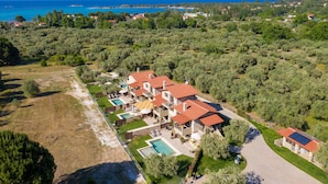 Vista aérea de una villa con varias habitaciones, piscina y vistas al mar.