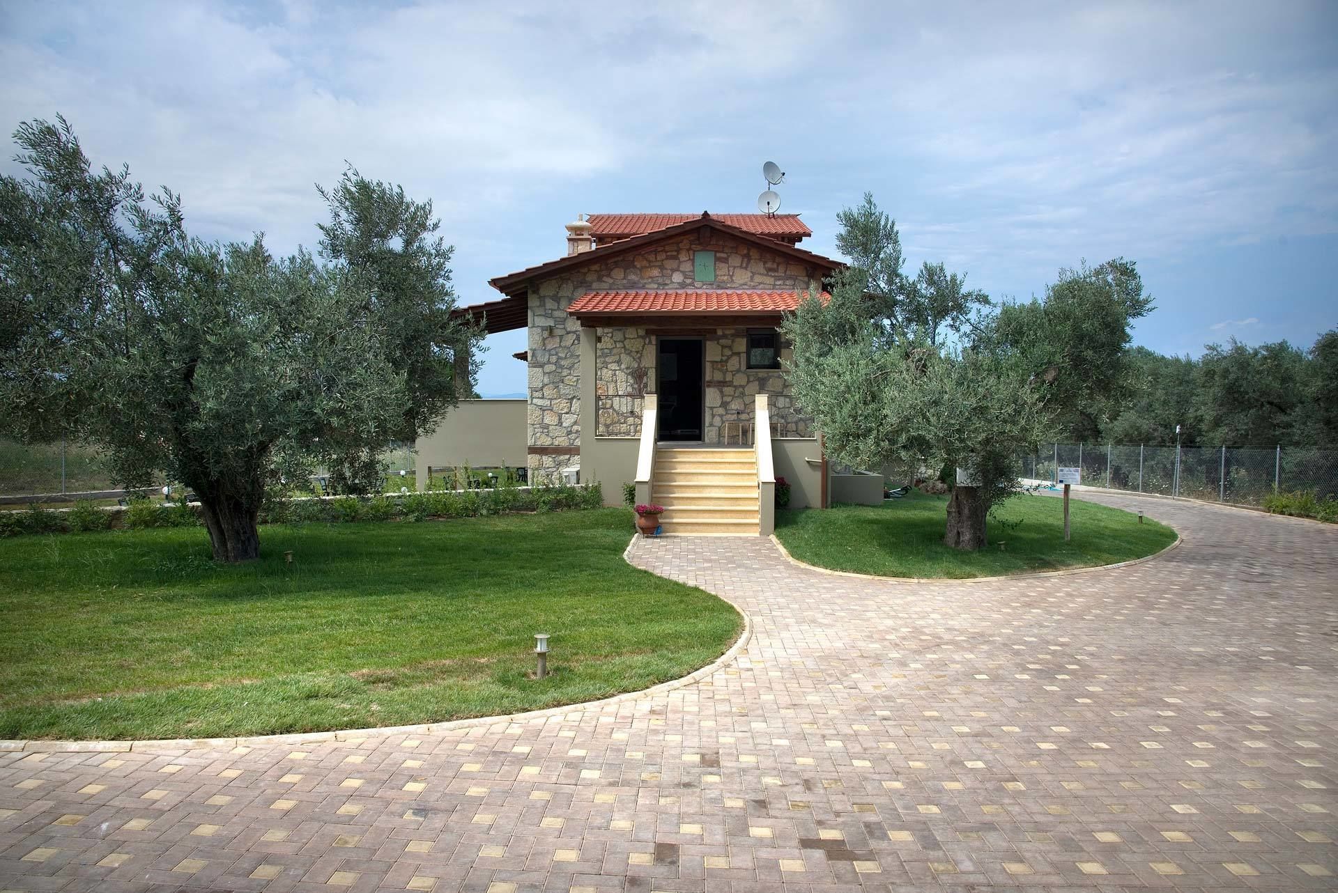 A stone building with a red-tiled roof, a staircase leading to the entrance, and a paved walkway.