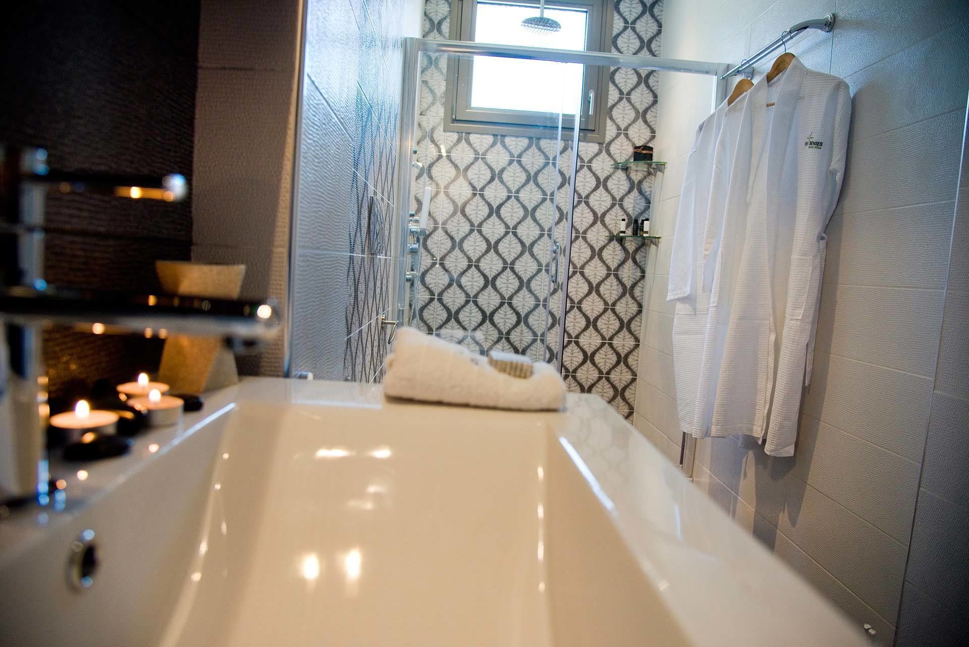 Un baño moderno con una bañera grande, una cabina de ducha con paredes de vidrio y toallas blancas colgadas en la pared.