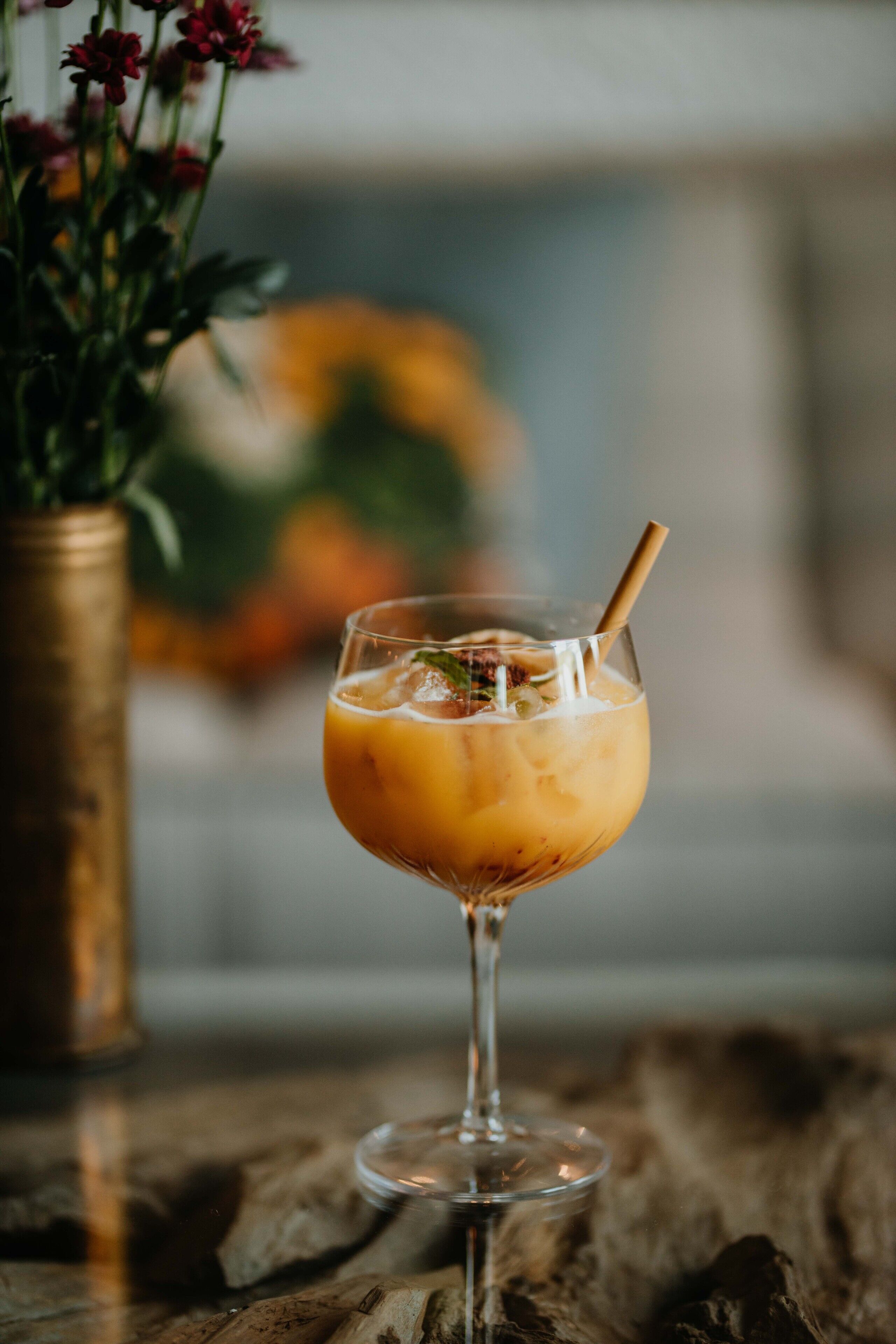 Een glas ijsthee met een rietje op een houten ondergrond.