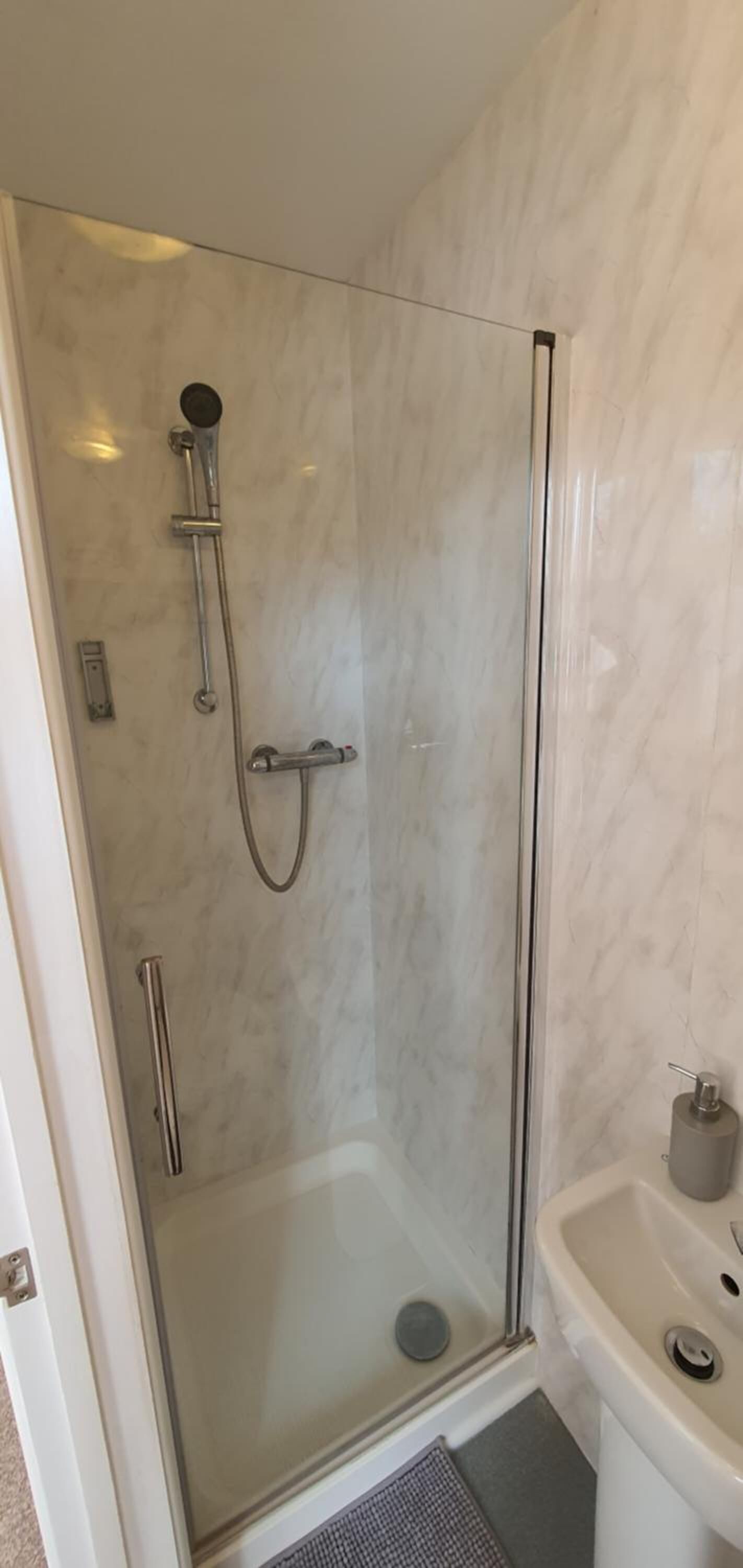 Um chuveiro com box de vidro e três chuveiros de mão.