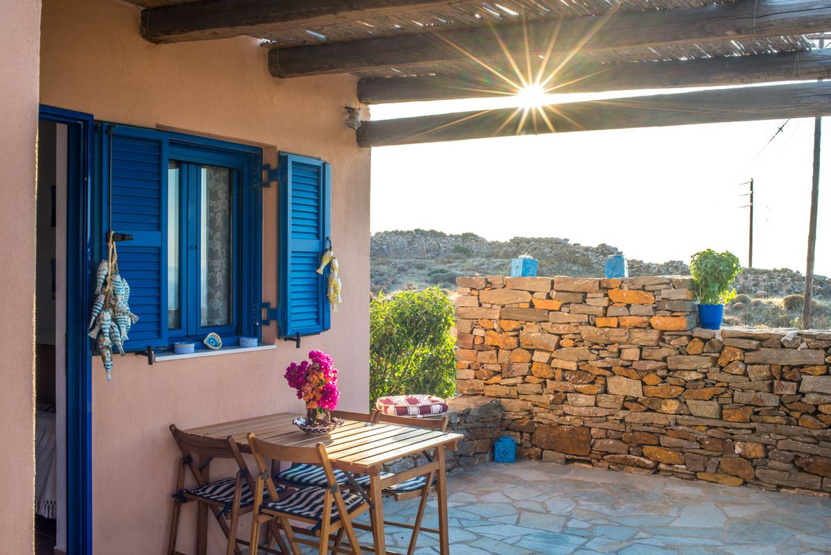 Eine Terrasse mit Tisch und Stühlen, eine Steinmauer und Blick auf die Landschaft.