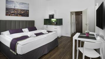 A hotel room with a bed, a desk, a chair, a TV, and a painting on the wall.