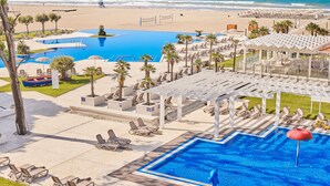 Ein Resort mit großem Pool, Zugang zum Strand und Sitzbereichen im Freien.