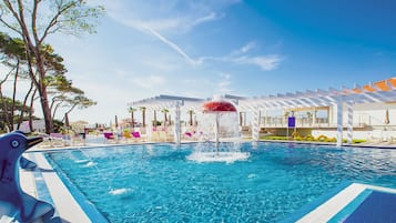 Relax by the pool surrounded by lounge chairs and umbrellas under a pergola.
