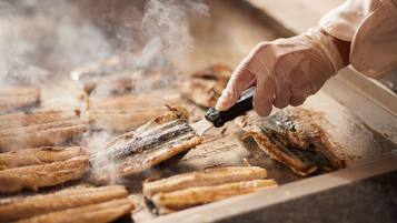A person grilling fish on a flat surface with steam rising.