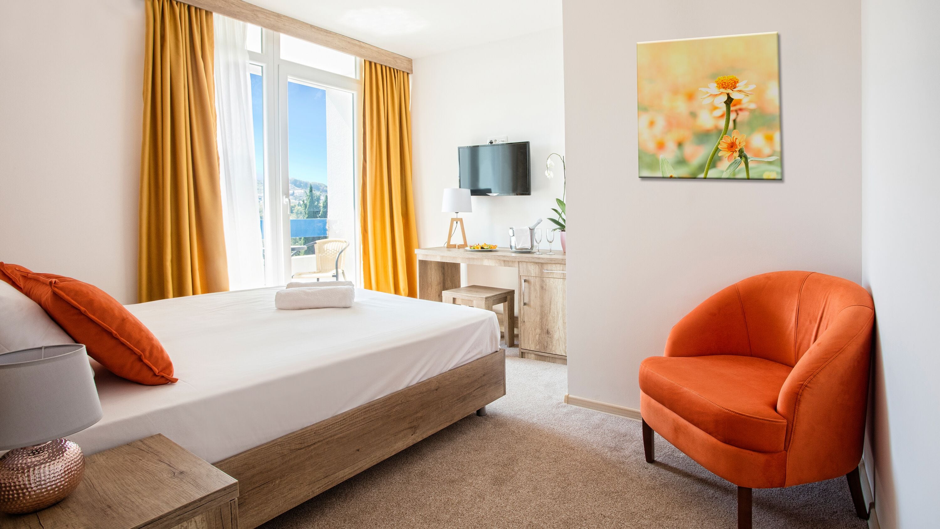 A hotel room with a bed, a desk, a chair, and a painting on the wall.