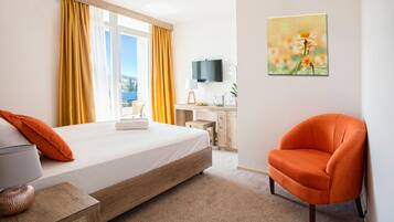 A hotel room with a bed, a desk, a chair, and a painting on the wall.